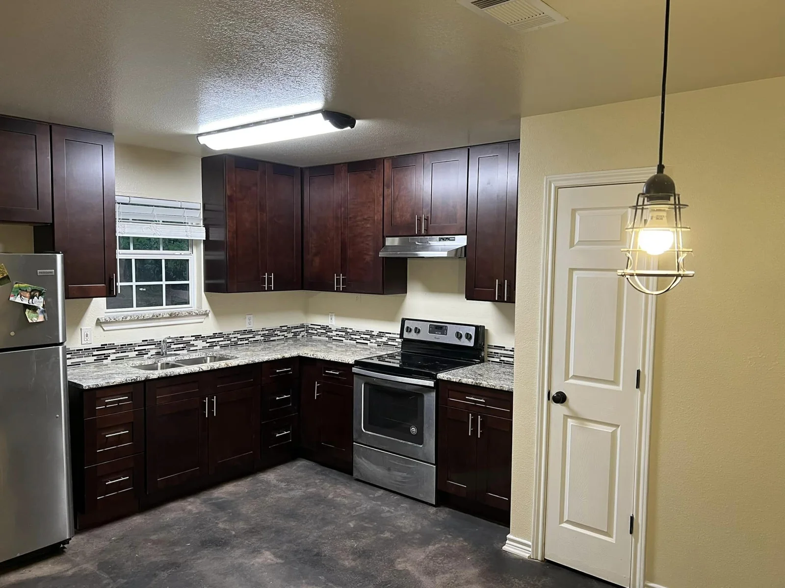 Kitchen with wood cabinets, a stove and pendant lighting at Eagle Inn Apartments