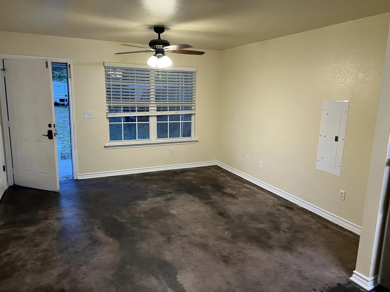 An unfurnished living space with a ceiling fan and windows